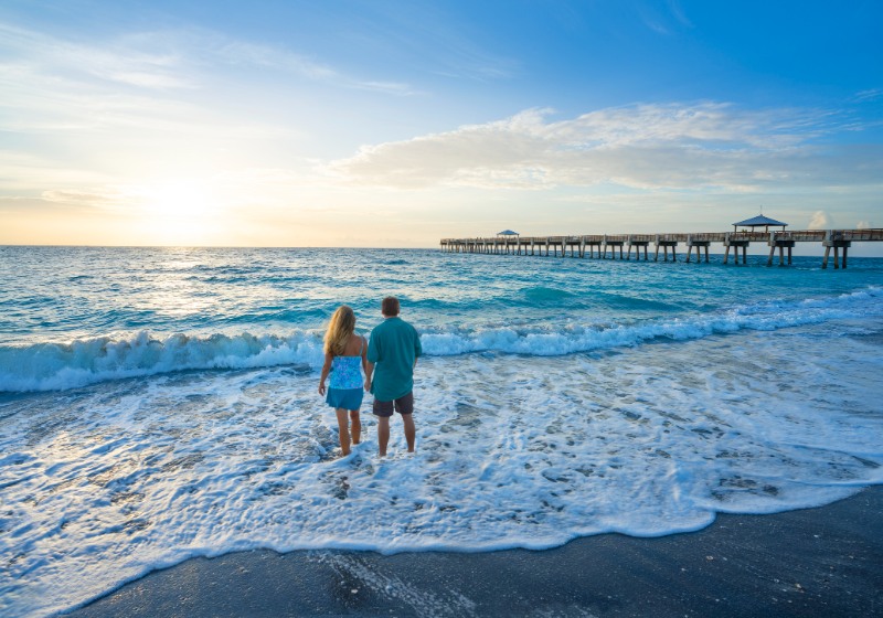 Couple standing on the beautiful beach at sunrise
